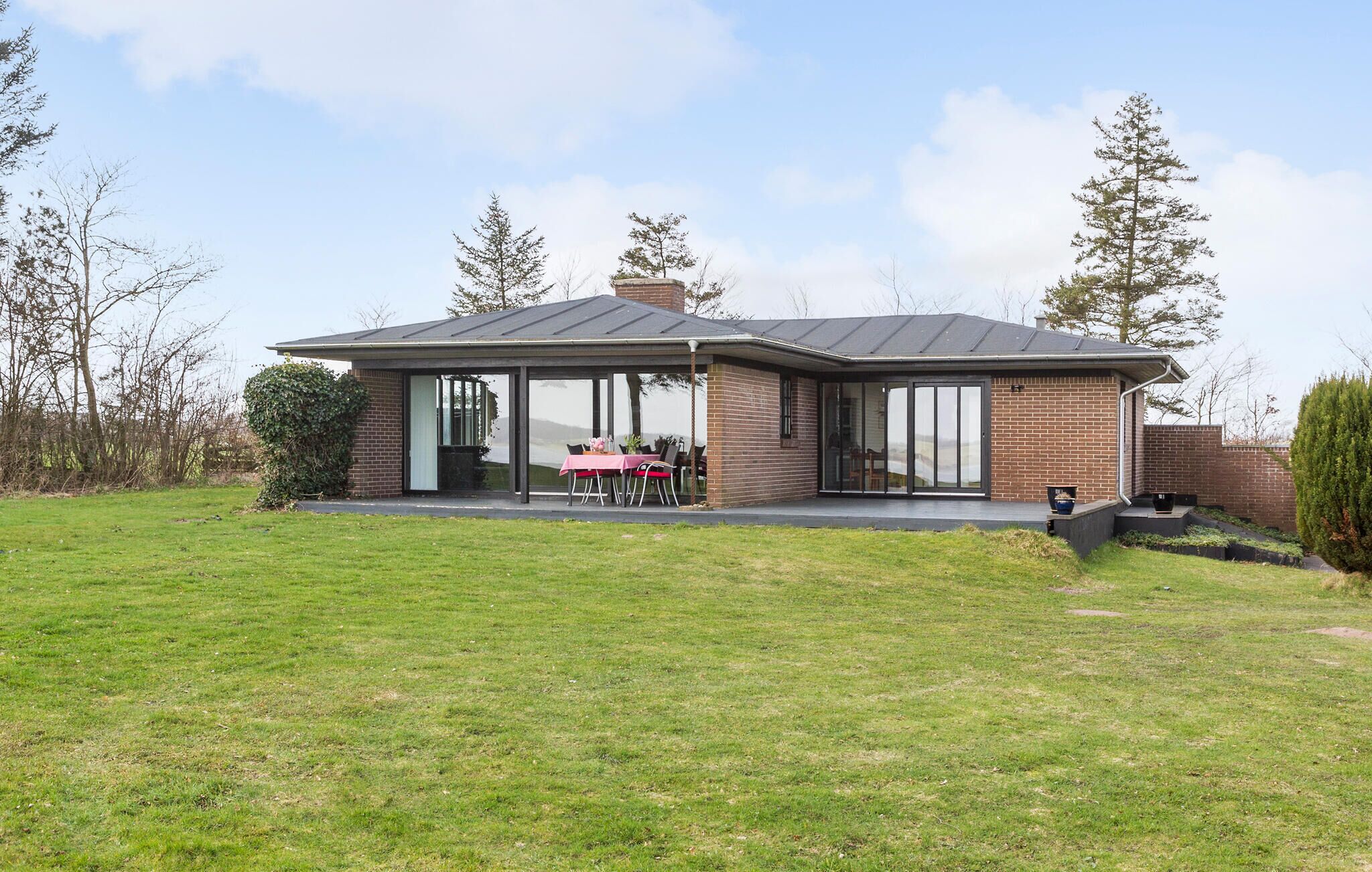 A modern house with a covered patio, brick exterior, and large glass doors.