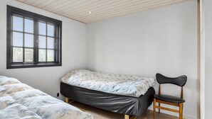A bedroom with a bed, a chair, a window, and a wooden ceiling. - Awesome home in Roslev with kitchen (Roslev)
