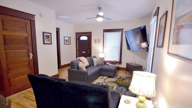A living room with a sectional sofa, a television, a lamp, and a door. - Bedford Bungalow (Bedford)