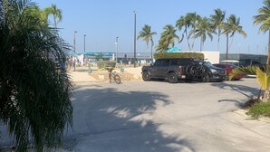 A parking area with vehicles, palm trees, and a clear sky. - Luxury Pull Thru Rv lot with access to all the Resorts amenities!  (Cudjoe Key)