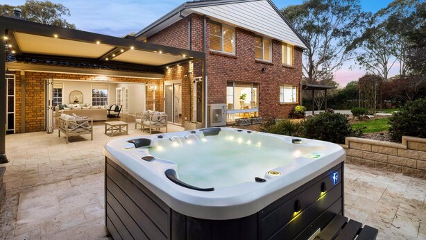 Et hus med jacuzzi, udendørs møbler og en overdækket terrasse.