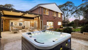 A house with a hot tub, outdoor seating, and a covered patio area.