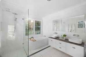 A modern bathroom with a glass-enclosed shower, a bathtub, and a vanity with a large mirror.