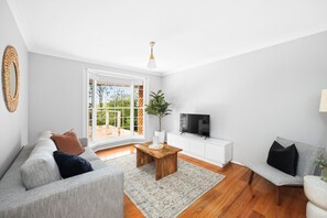 A modern living room with a sofa, a coffee table, a TV, and a plant.