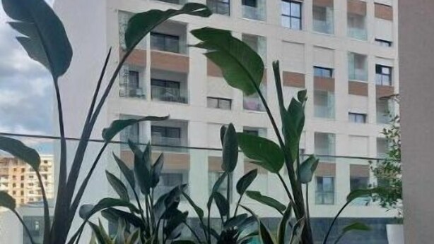 Een modern appartement met een groot raam, een balkon en uitzicht op een hoog gebouw.