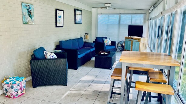 A spacious living area with a blue sofa set, a wooden table, and a TV. - Mermaid Dreams: Spacious 3 bedrooms 2.5 bath with pool ALL in golf cart district (Ocean Springs)