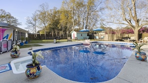 A backyard with a swimming pool, potted plants, outdoor furniture, and a house in the background. - Mermaid Dreams: Spacious 3 bedrooms 2.5 bath with pool ALL in golf cart district (Ocean Springs)