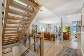 A spacious living area with a wooden staircase, a sofa set, and a large window providing a view of the outdoors. - Falcons Overlook (Monument)
