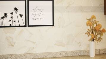 A wall with two framed pictures and a vase with dried flowers.
