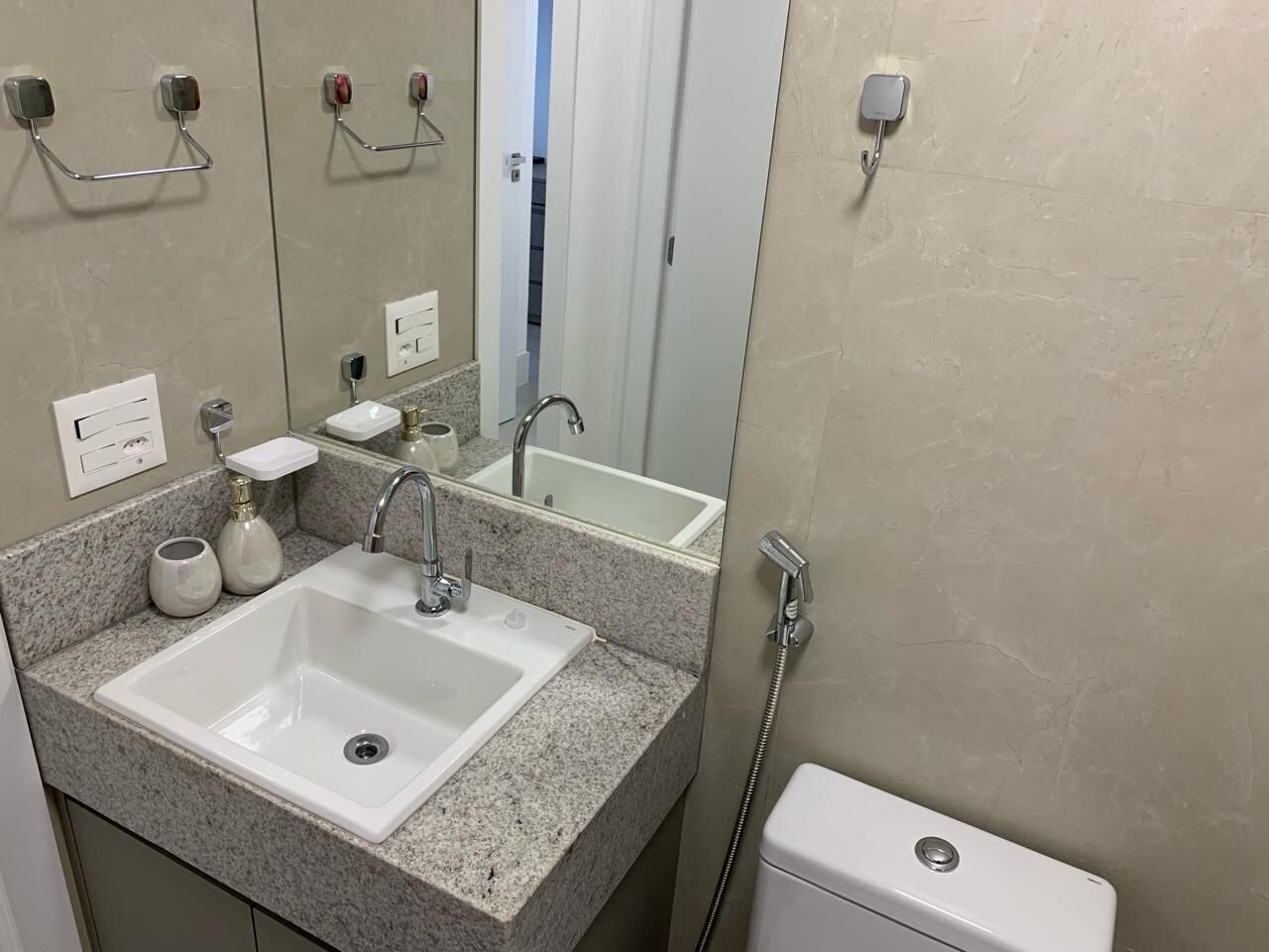 Un bagno con un lavandino bianco, uno specchio, un portasciugamani, un erogatore di sapone e un WC.
