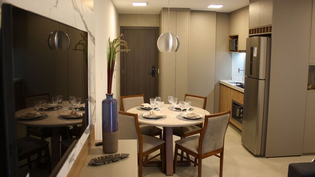 Une cuisine moderne dotée d’un réfrigérateur encastré, d’une table à manger pour quatre personnes et d’un vase avec des plantes.