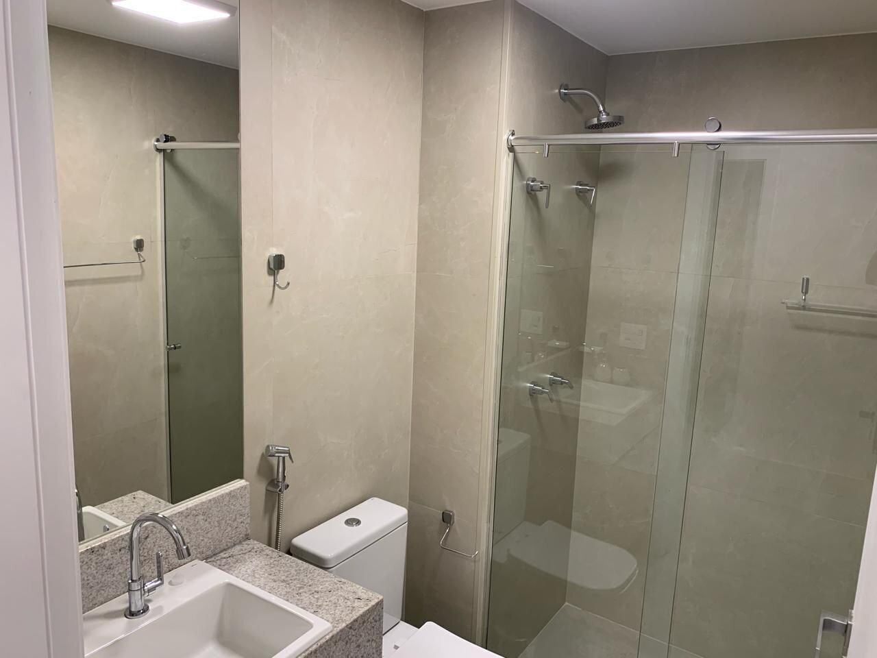 A modern bathroom with a glass-enclosed shower, a sink with a mirror, and a toilet.