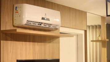 A white air conditioning unit mounted on a wooden wall with a built-in television below it.