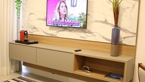 Un salon moderne avec un téléviseur à écran plat fixé à un mur en marbre, une console en bois sur laquelle est posé un vase, et un tapis à motifs rayés.