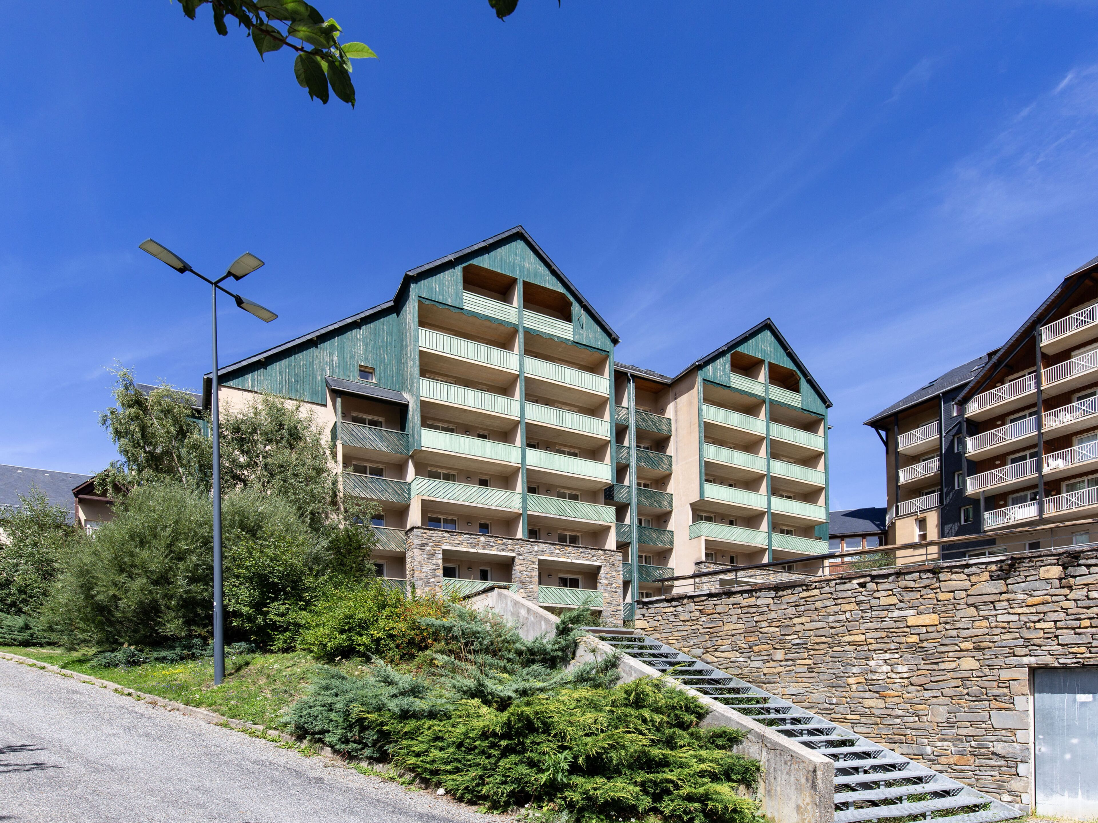 Un hôtel à plusieurs étages, doté d’une façade en pierre, de nombreux balcons et d’un escalier menant à l’entrée.