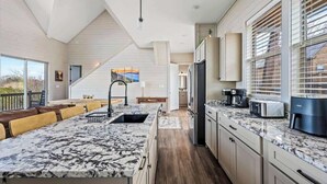 A modern kitchen with a large island, built-in appliances, and a view to the outdoors. - NEW LAKE CABIN Sleeps 14 Indoor Pool Hot Tub (Sevierville)