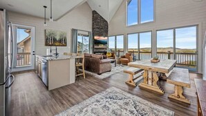 A spacious living area with a large window, a fireplace, and a dining table. - NEW LAKE CABIN Sleeps 14 Indoor Pool Hot Tub (Sevierville)