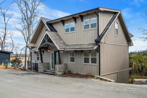 A two-story house with a gabled roof, a stone foundation, and a small front porch.