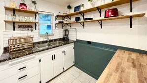 A kitchen with white cabinets, a granite countertop, and wooden shelves. - Lake Life Lodge Cottage by Belton Lake (Belton)