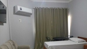 Habitación de hotel con dos camas, un sofá, un escritorio y un equipo de aire acondicionado.