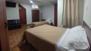 Une chambre d’hôtel avec deux lits, une armoire, un bureau et une chaise.