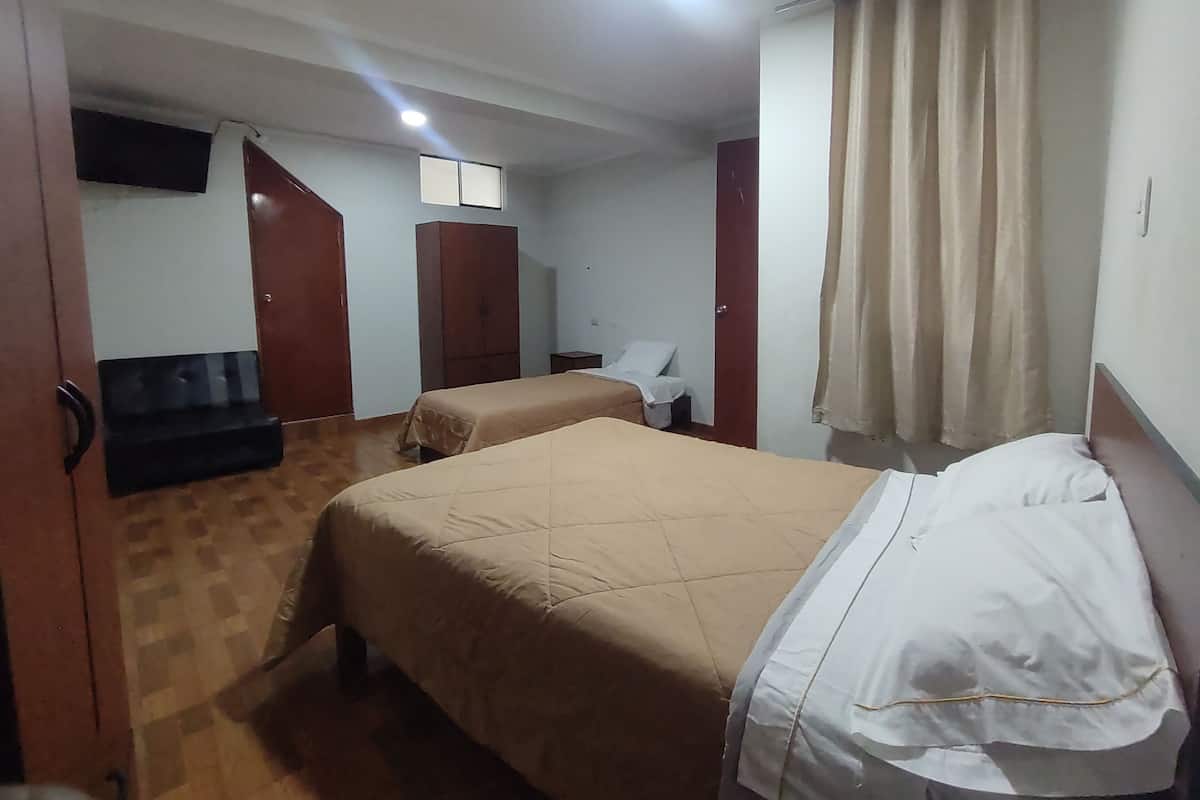Une chambre d’hôtel avec deux lits, une armoire, un bureau et une chaise.