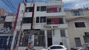 Un immeuble à plusieurs étages avec une enseigne indiquant « Hôtel Yuraq Wasi ».