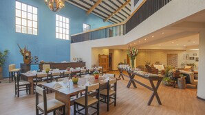 A spacious dining area with multiple tables and chairs, a wooden ceiling, and large windows allowing natural light. - Lamay Lodge by Mountain Lodges of Peru (Lamay)