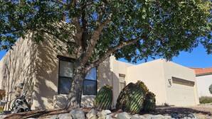 A building with a tree in front, a garage, and a cactus. - Breathtaking views in Tucson - Relax and refresh in a peaceful neighborhood.  (Tucson)