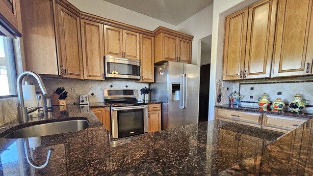 A kitchen with granite countertops, stainless steel appliances, wooden cabinets, and a stainless steel sink. - Breathtaking views in Tucson - Relax and refresh in a peaceful neighborhood.  (Tucson)