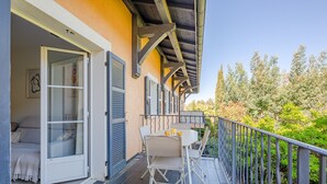 A balcony with a table and chairs, a bed with a view, and a railing.