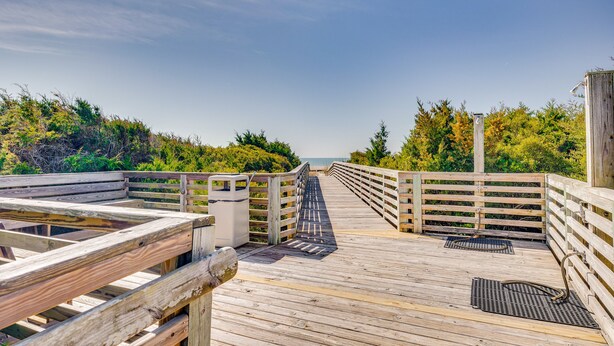 A wooden boardwalk leading to a beach with a railing on one side and dense foliage on the other. - Atlantic Beach Condo w/ Balcony & Beach Access! (Atlantic Beach)