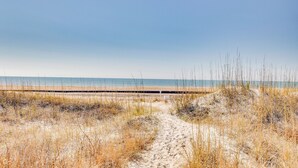 A sandy beach path leading to the ocean with a wooden boardwalk in the distance. - Atlantic Beach Condo w/ Balcony & Beach Access! (Atlantic Beach)