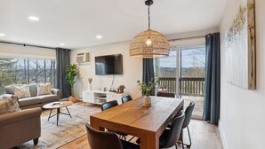 Una sala moderna con una mesa de comedor de madera, sofá y televisor.