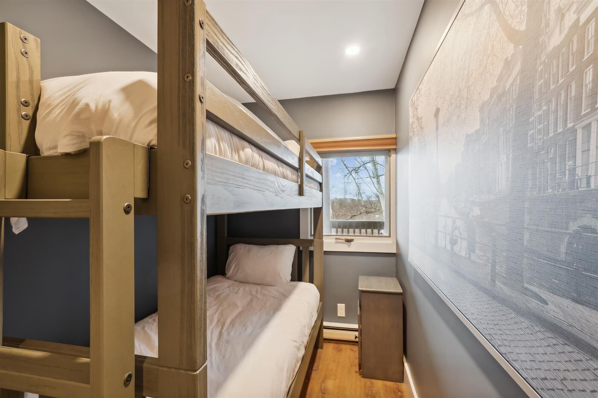 A bunk bed room with a window and a wall-mounted artwork.