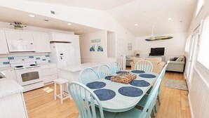 Una cocina moderna con armarios blancos, un microondas y una estufa. Cuenta con un comedor con mesa y sillas.
