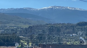Paesaggio montuoso con cime innevate all'orizzonte e una valle punteggiata di edifici.