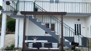 A two-story building with a balcony, a staircase, and a stone planter. - Apartment 'Alojamento D Duarte T1' with Mountain View, Balcony and Wi-Fi (Gouveia)