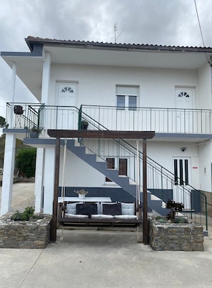 Un bâtiment à deux étages doté d’un balcon, d’un escalier et d’un jardinier en pierre.