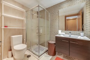 Une salle de bain moderne avec une douche à parois de verre, des toilettes, un meuble-lavabo avec un miroir et un mur décoré d’un motif.