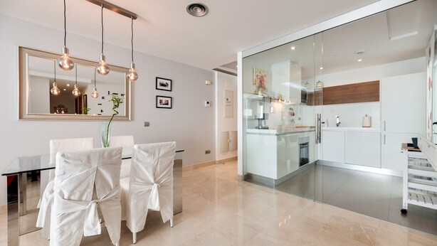 Una cocina moderna con armarios blancos, protector contra salpicaduras de vidrio y electrodomésticos de acero inoxidable.
