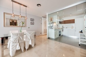 A modern kitchen with white cabinets, a glass backsplash, and stainless steel appliances.