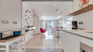 Una cocina moderna con cafetera, tostadora y una silla roja.