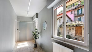 A hallway with a potted plant, a radiator, and a window with a view of buildings. - Holiday Apartment "Dongo Garden" with Private Garden & Wi-Fi (Dongo)
