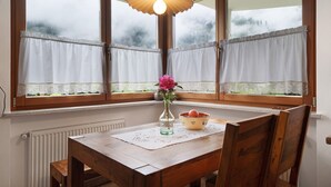 A dining area with a table, chairs, a vase with flowers, and a bowl on the table.