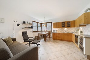 Una cocina moderna con armarios de madera, un comedor con mesa y sillas, y un sofá en la sala de estar.