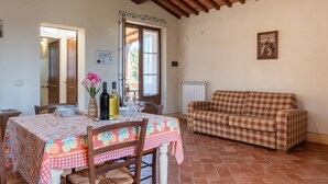 Un coin repas avec une table dressée pour deux personnes, un canapé à carreaux et une fenêtre donnant sur un beau paysage.
