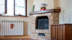 Une pièce avec une cheminée, un radiateur et une fenêtre avec des rideaux.