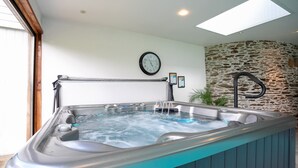 Ein Whirlpool mit Metallrahmen, eine Uhr an der Wand und eine Steinwand im Hintergrund.