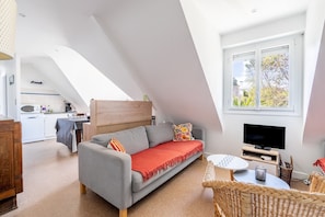 Een kamer in loftstijl met een bank, televisie en eethoek.
